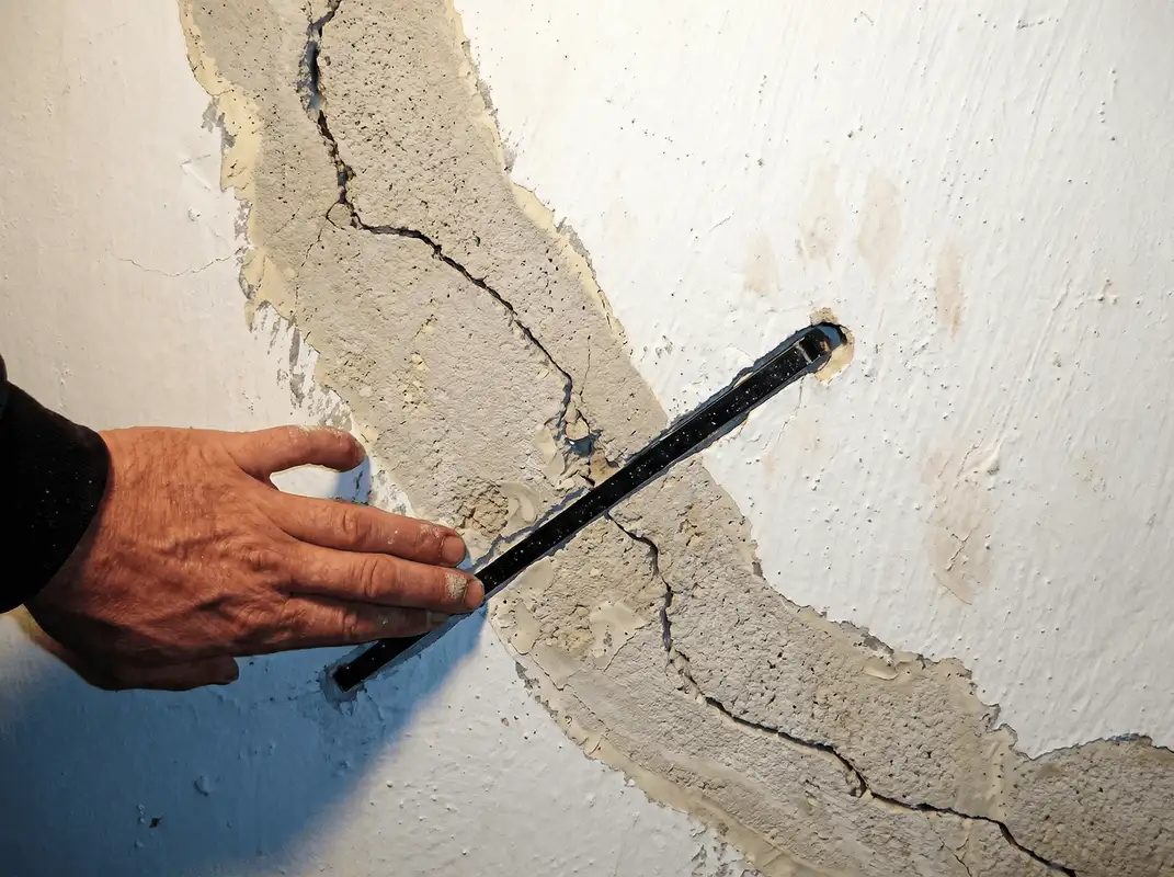 A wall with a large crack is being inspected by a professional in Norfolk, VA